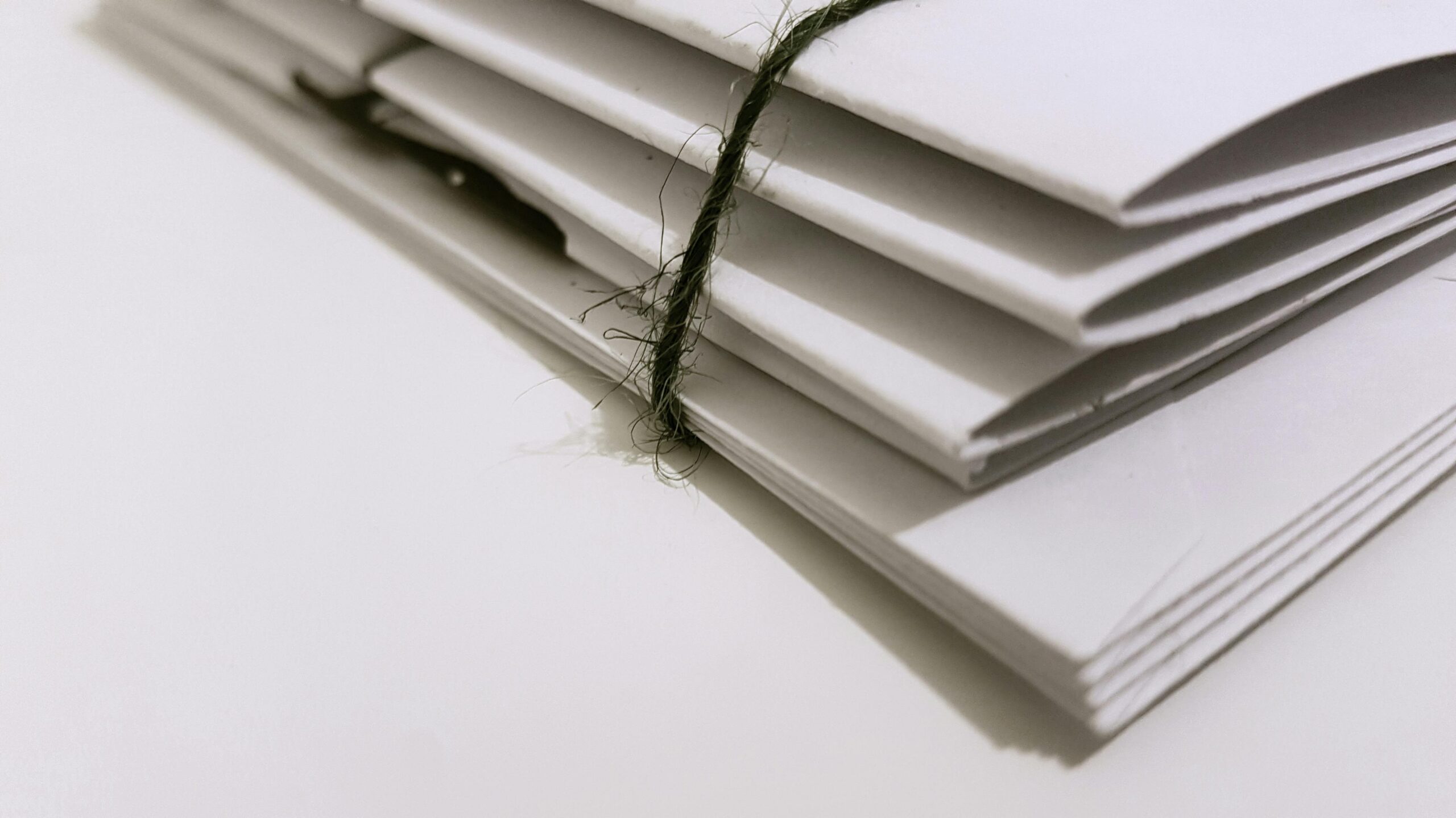 A stack of white folded papers tied together with a piece of black string.