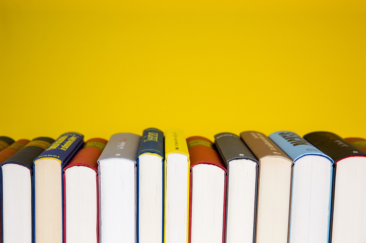 Row of books with colorful spines against a yellow background.