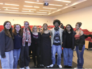 Dr. Christine Altinis-Kiraz stands with a small group of students in a classroom, all smiling and casually dressed for a group photo.