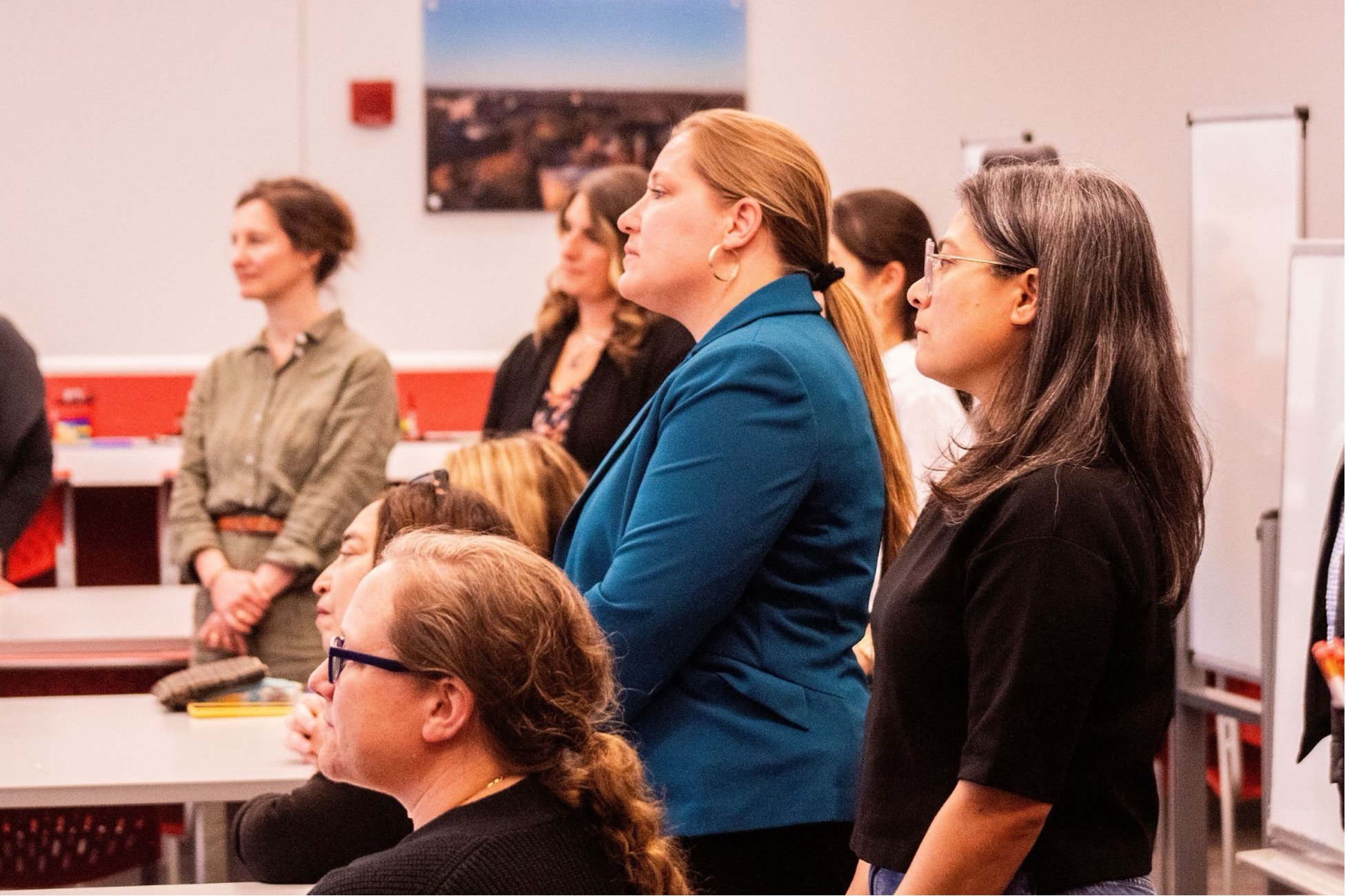 A group of attendees stands attentively during a session at the Course Design Institute.