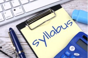 The word syllabus on a clipboard next to a laptop