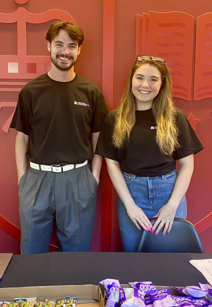 Two people standing in front of a table of snacks smiling
