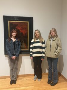 Three students stand in front of picture at Zimmerli Art Museum. 