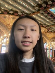 Headshot of undergraduate student fellow, Amber Yu, wearing a black shirt, and standing in an ornate, decorative room.