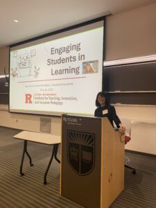 This image shows a conference room with PPT slides projected onto a screen. The screen reads "Engaging Students in Learning". The facilitator is at the podium, smiling.