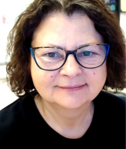 A woman with short brown hair, glasses, and a black shirt, smiling.